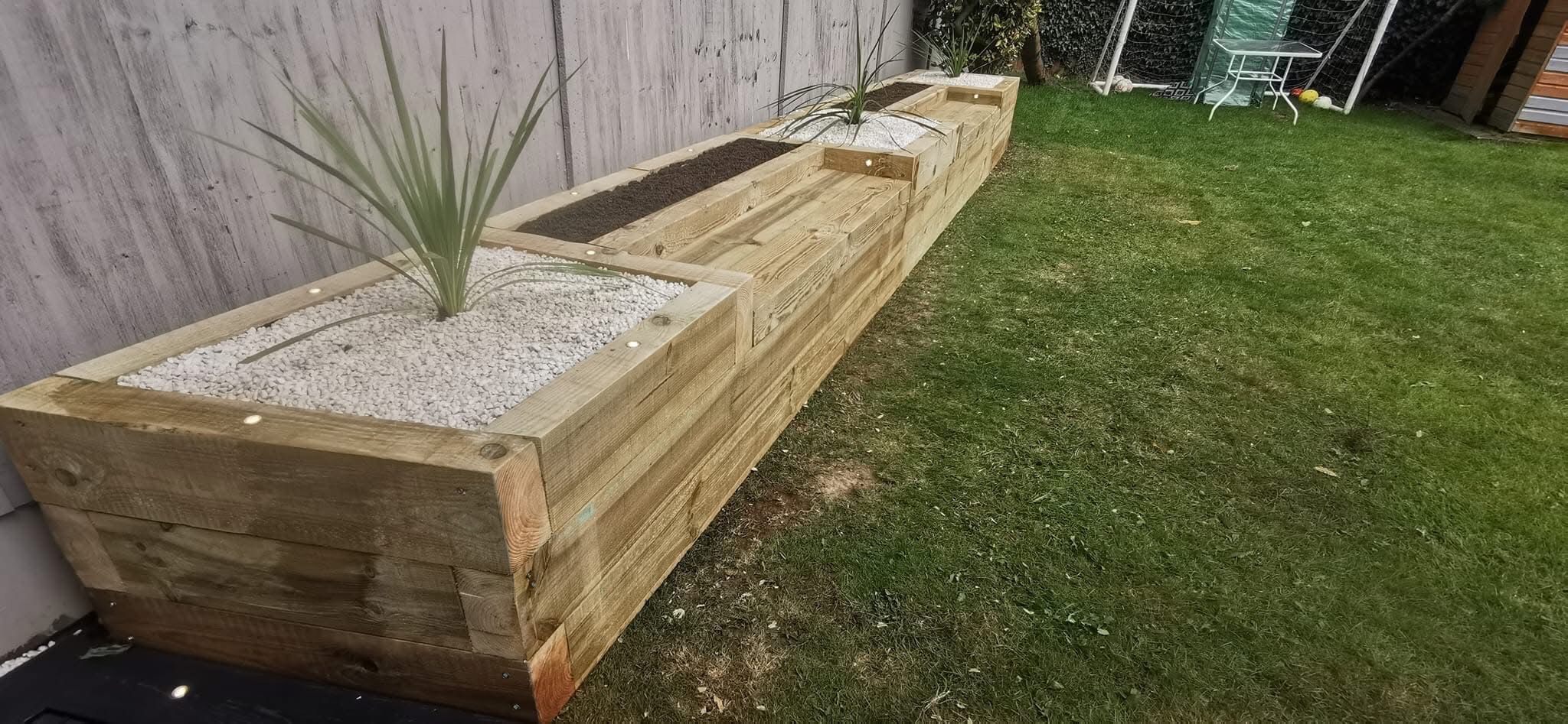 Timber sleeper raised planters running along a lawn