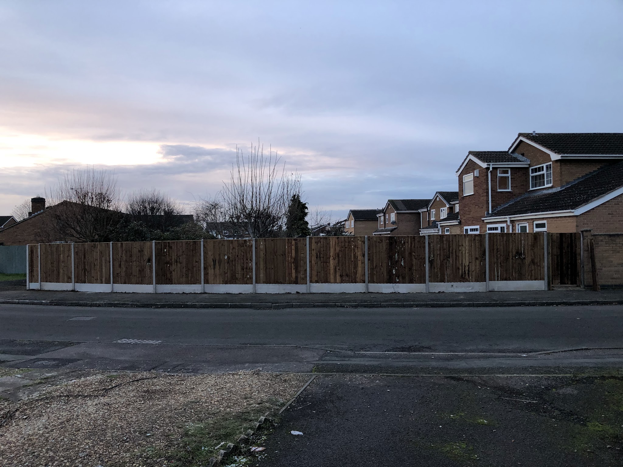 Panel fencing on concrete gravel boards along a roadside boundary
