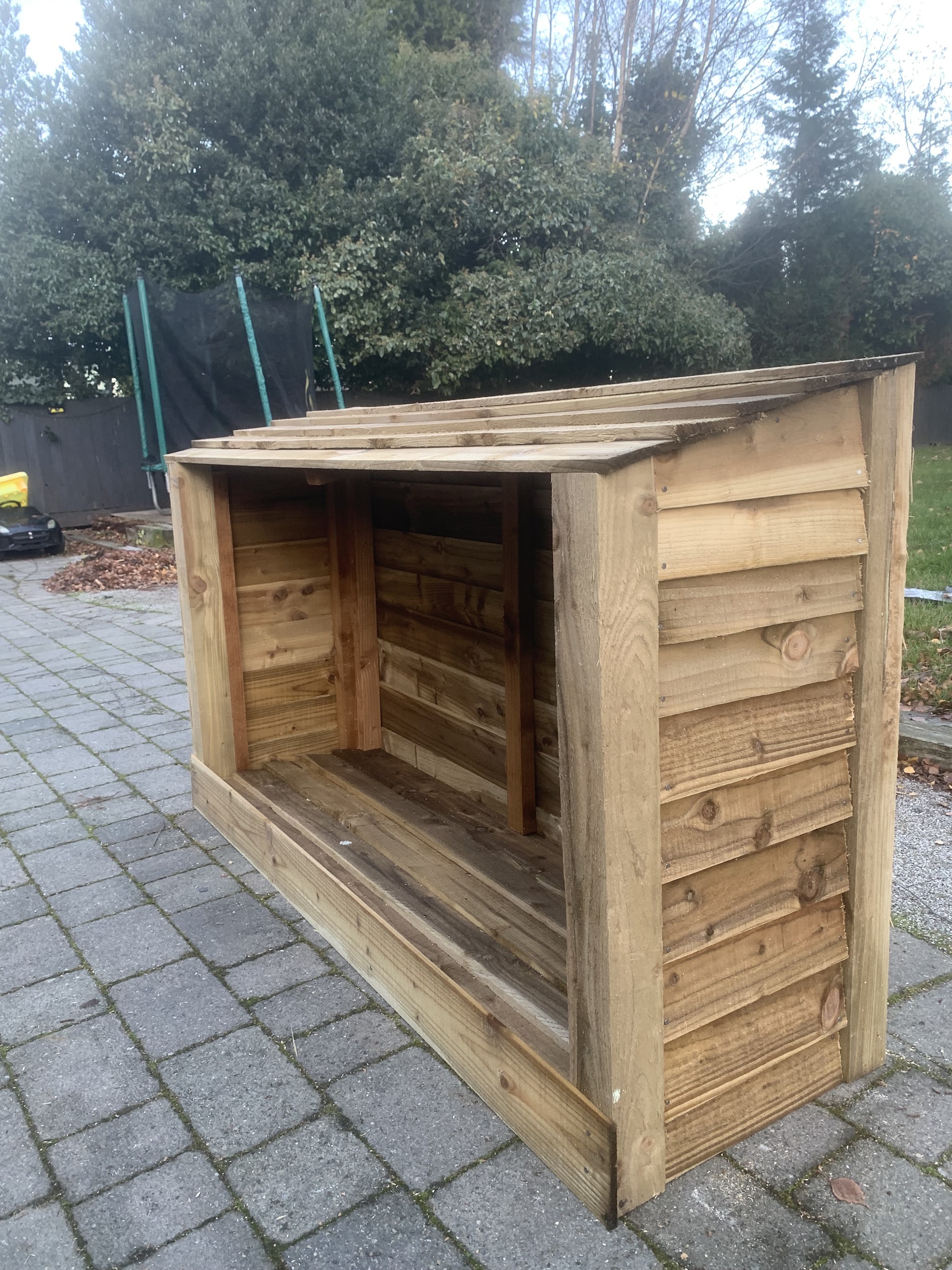 Timber log store standing on block paving